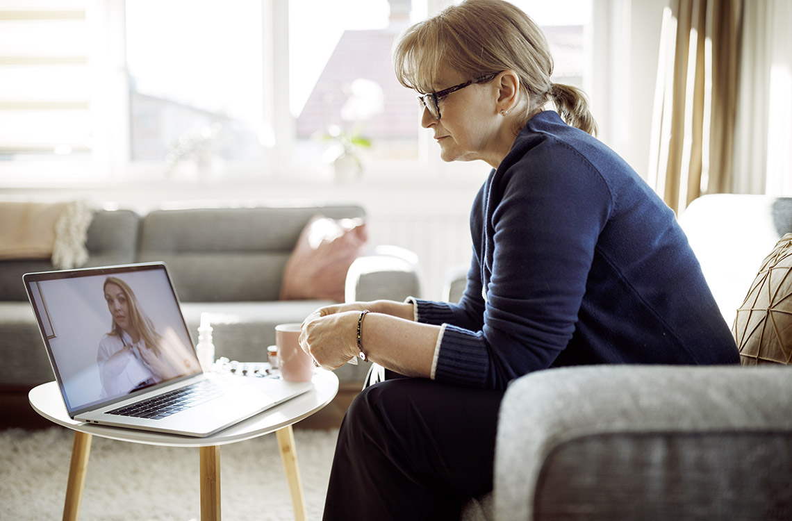 En kvinna sitter i soffan och tittar på datorskärmen.